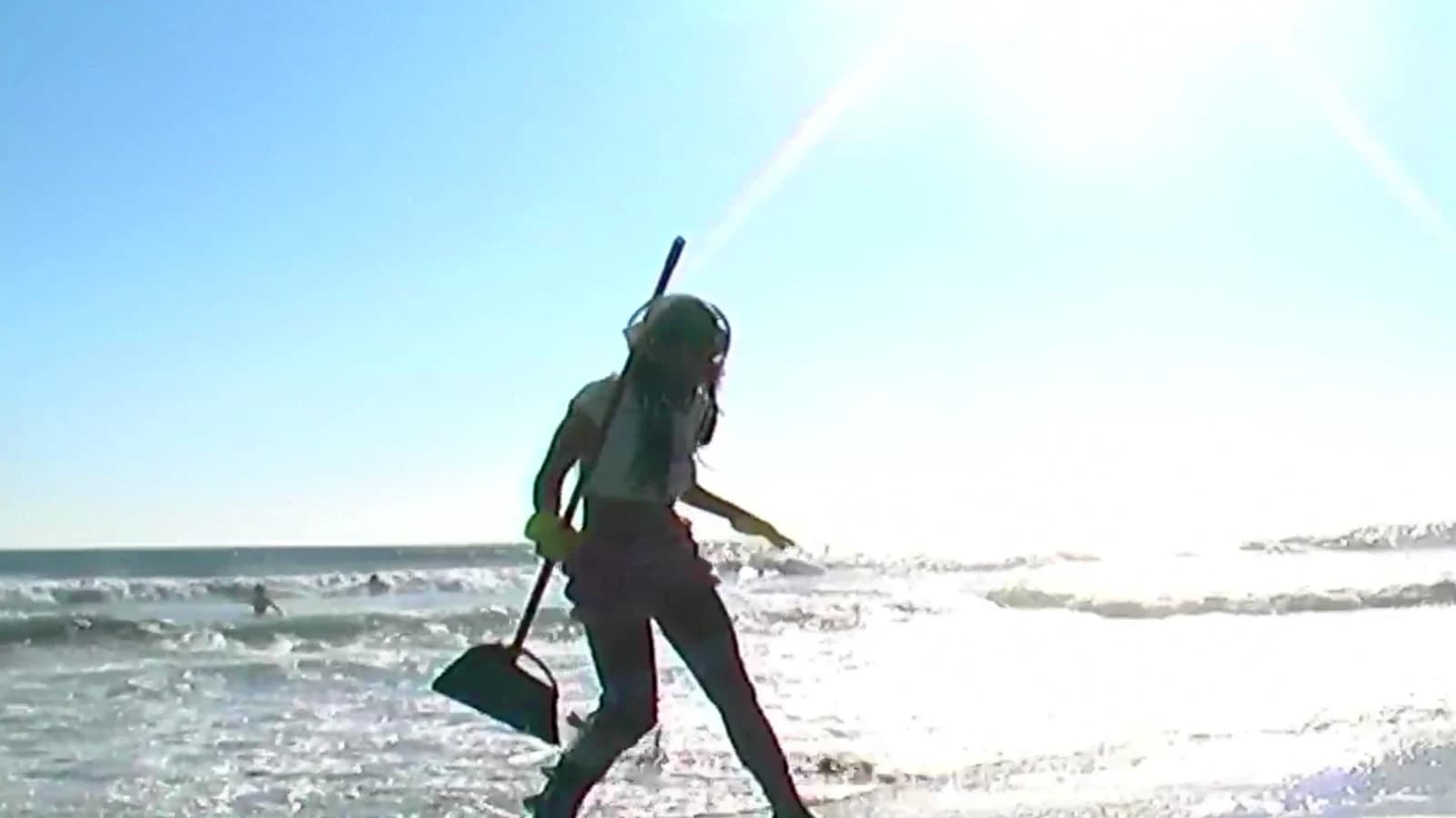Walking through the sparkling surf with a broom