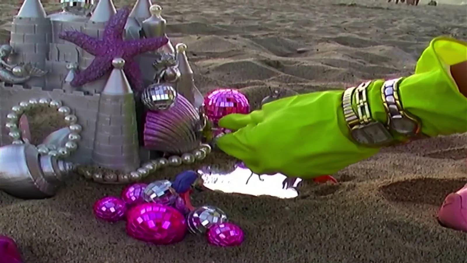 Neon gloves arranging silver and pink beach treasures