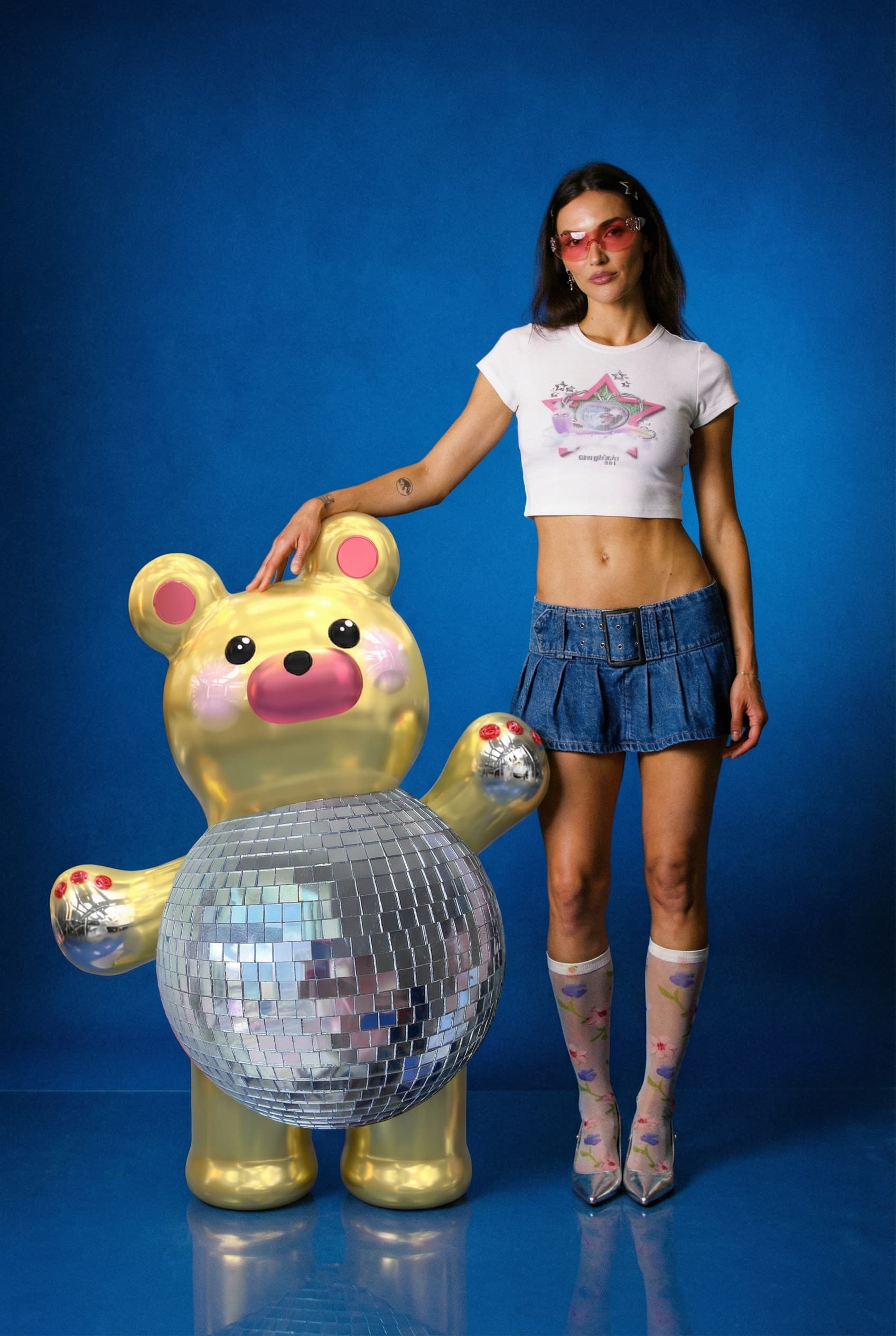 Hailee standing beside Arny, the golden bear with a mirrored disco-ball belly